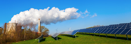 field with solar collectors and fossil-fuel power station