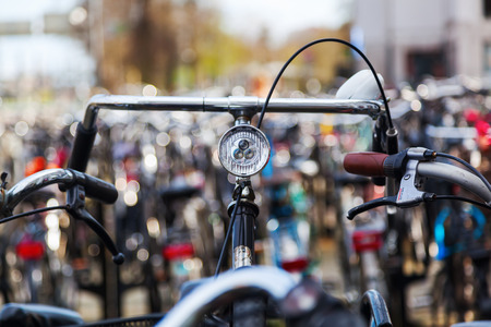 handlebar of a bicycle standing between others at a bicycle parking lotの写真素材