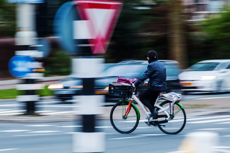 bicycle rider in city traffic shown in motion blurの写真素材