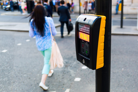 pedestrian button at a pedestrian crossing in London, UK, with blurred pedestrians in the backgroundの写真素材