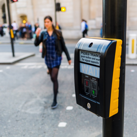 pedestrian button at a pedestrian crossing in London, UK, with blurred pedestrians in the backgroundの写真素材