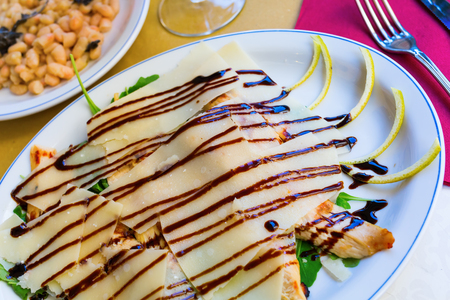 plate with chicken breast covered with parmesan cheese and chickpeas in the backgroundの写真素材