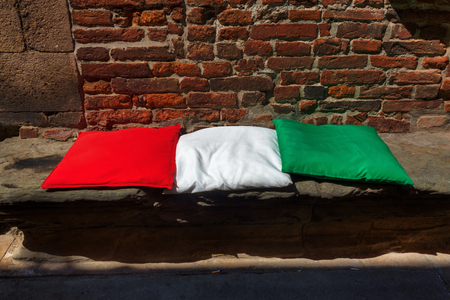 three pillows in color of the Italian national flag on a stone benchの写真素材