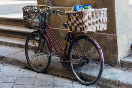 old bicycle with baskets leaning against a column in Florence, Italy