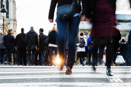 picture with motion blur of a crowd of people crossing a city street at the pedestrian crossing