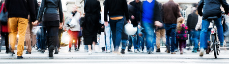 picture with motion blur of a crowd of people crossing a city street at the pedestrian crossing