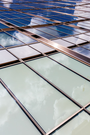 glass facade of an office building with reflection of the skyの写真素材