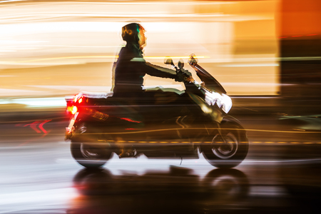 picture with camera made motion blur effect of a motorcycle rider at night trafficの写真素材