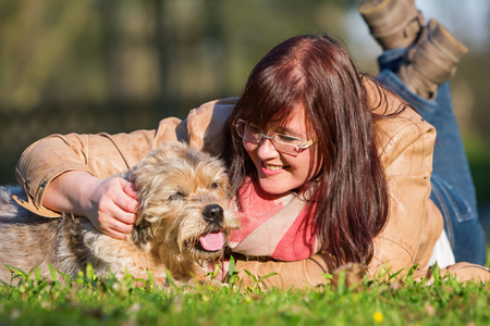 portrait of a young woman lying with her dog in the grassのeditorial素材