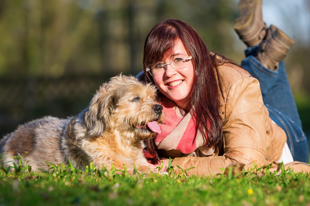 portrait of a young woman lying with her dog in the grassのeditorial素材