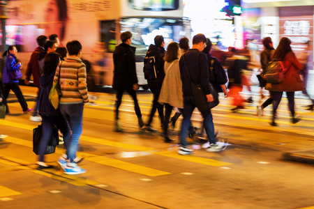 picture in motion blur of a crowd of people crossing a street at nightの写真素材