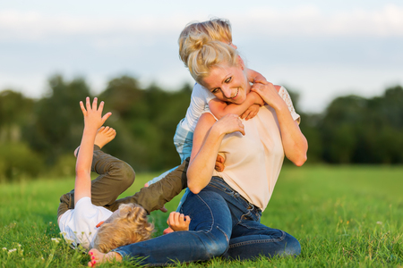 picture of a woman who romps with her two sons on the grassの写真素材