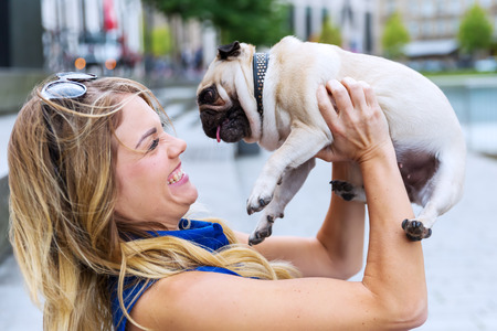 young woman has fun by raising up her cute pug andの写真素材