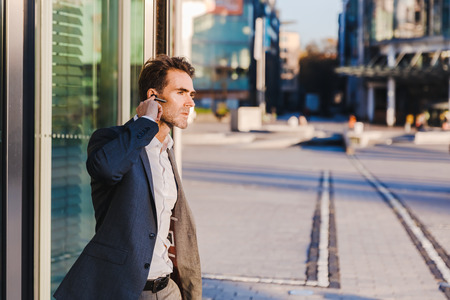 businessman with earphones comes out of a revolving door of an office buildingの写真素材