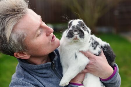 mature woman holds a pet rabbit in the arms