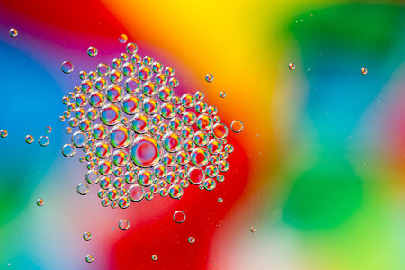 Oil drops in water on a coloured background