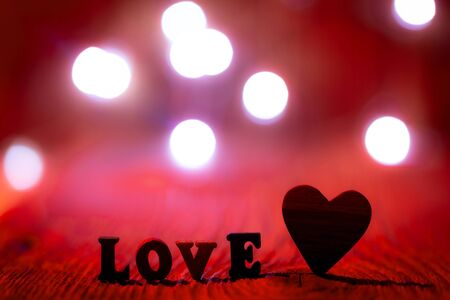 Inscription love and wooden heart on a blurred background.の写真素材