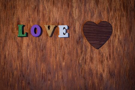 Inscription love and wooden heart on the backgroundの写真素材