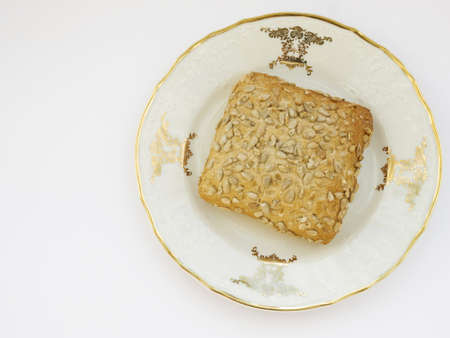 Sunflower bun on porcelain decorated plate on white background, photo