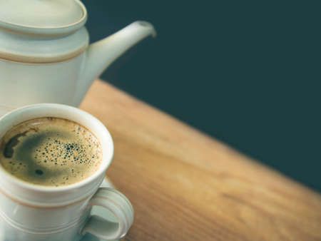 A cup of coffee, in a white cup on a wooden table, blurred background photo