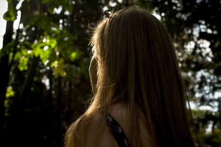 A shot made to a girl watching the light from a forestの写真素材