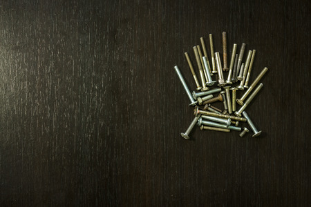 A few arranged screws on a dark wooden backgroundの写真素材