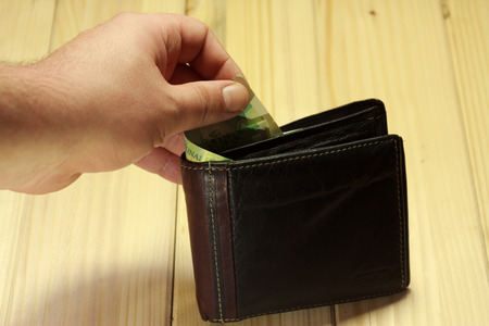 Shot of a hand taking some romanian money out from a wallet standing on a wooden tableの写真素材