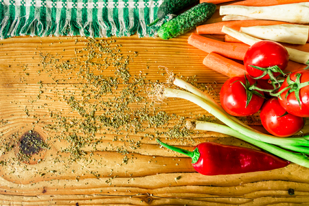 Vegetables next to a green plaid towel on a wooden table salted with oreganoの写真素材