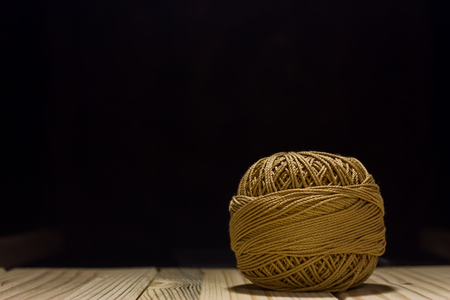 Shot of a ball of thread in a dark black background on a wooden tableの写真素材