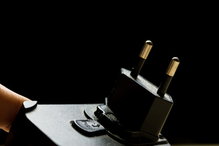 Closeup shot of a finger holding a charger with a dark black backgroundの写真素材