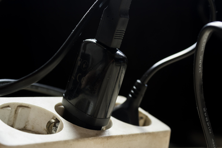 Electrical socket with a few chargers in it on a dark black backgroundの写真素材