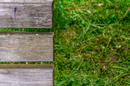 Closeup shot to half of a bench in a park with grass in backgroundの写真素材