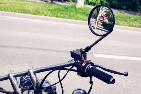 Closeup shot to a motorcycle handle bar with mirror view parked on a lone streetの写真素材
