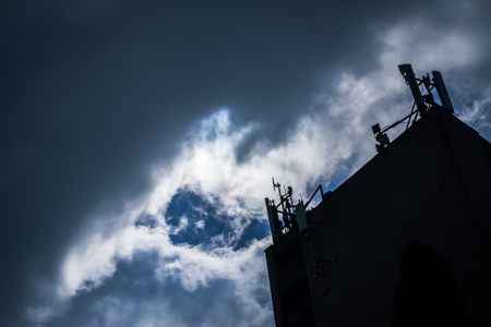 Storm clouds gathered over a building that looks like a meteorology postの写真素材