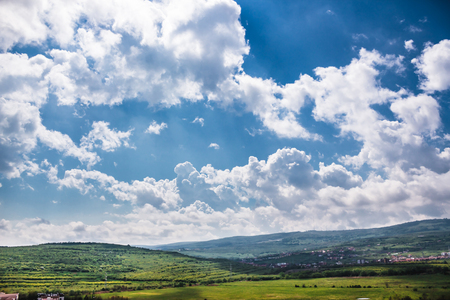 Fantastic landscape of a few trees, some distant hills and clouds preparing to start a stormの写真素材