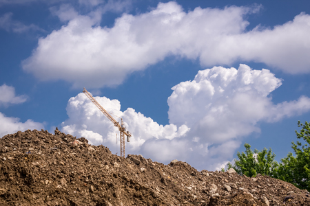 Shot to a distant crane over a mound of dirt with detailed clouds in the backgroundの写真素材