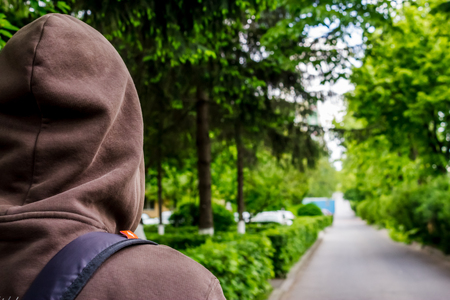 Close up shot to a guy with hood and a backpack looking in the distanceの写真素材