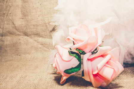 Shot to a few roses on burlap fabric with a few white feathersの写真素材