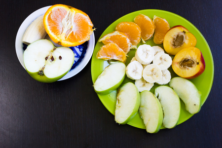Summer tasty fruits on a few plates and a dark backgroundの写真素材
