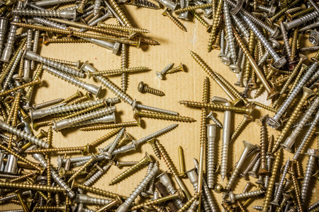 Shot to a few scattered screws on the floor on a yellow backgroundの写真素材