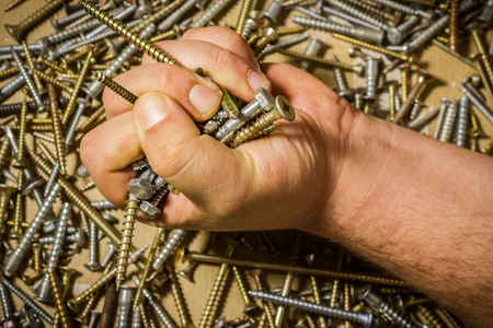 Shot to a male hand holdinng screws in his fist really tightの写真素材