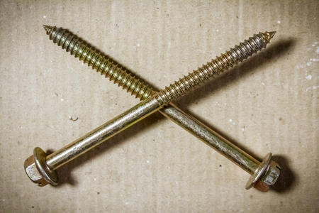 Two crossed screws on a plain cardboardの写真素材