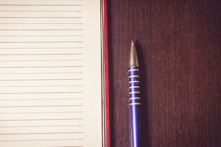 Close up shot to a pen next to an agenda on a wooden backgroundの写真素材