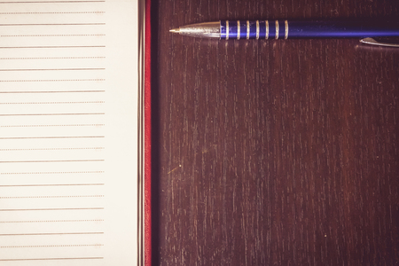 Close up shot to a pen next to an agenda on a wooden backgroundの写真素材
