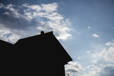 Completely dark silhouette of a house with a cloudy sky in the background in the summer timeの写真素材