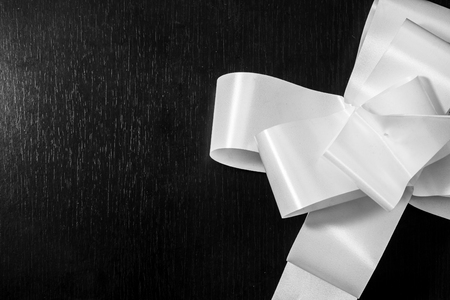 Close up shot to a beautiful white bow on a dark wooden backgroundの写真素材