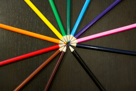 Well arranges colored pencils in order to form rainbow colors on a dark wooden backroundの写真素材