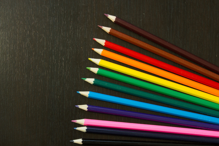 Well arranges colored pencils in order to form rainbow colors on a dark wooden backroundの写真素材