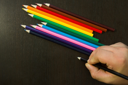 Well arranges colored pencils in order to form rainbow colors on a dark wooden backround with a hand writing with black pencil near themの写真素材