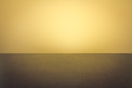 A dark wooden table with yellow backgroundの写真素材